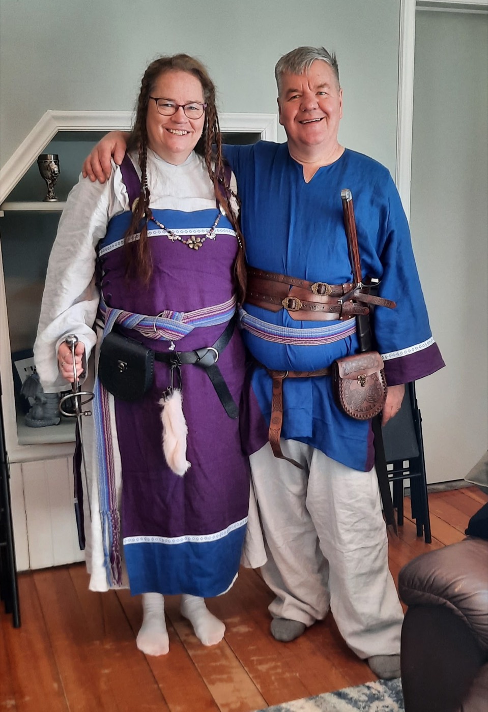 Toby Leonard in blue tunic and belted leather, in historical dress at home